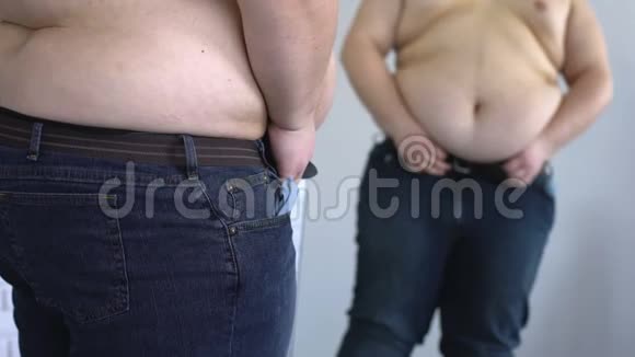 超重的人在肥胖的腹部下收紧牛仔裤腰带暴饮暴食肥胖视频的预览图