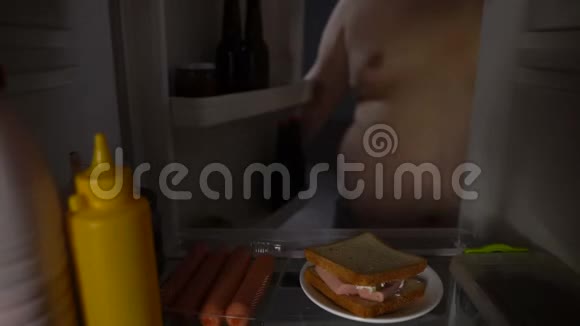 肥胖男性从冰箱里拿三明治不健康的营养久坐的生活方式视频的预览图