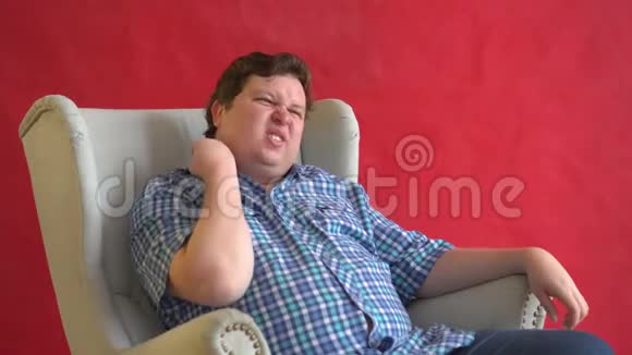 胖子坐在椅子上脖子疼被隔离在红色背景上视频的预览图