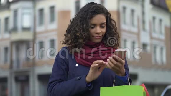 混合种族妇女在现代智能手机上查看网上商店应用程序购物视频的预览图