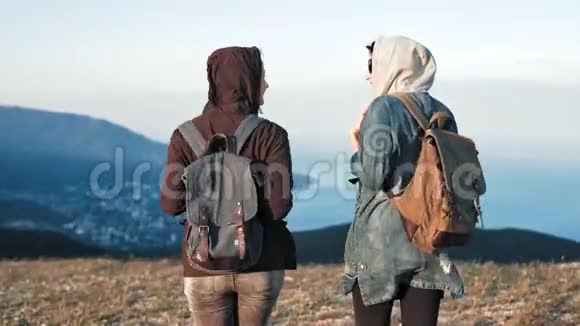 两名年轻女子背着背包在山岩漫步背景是美丽的自然景观视频的预览图