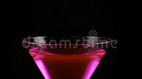 女人手在黑暗中准备一杯带樱桃的粉红色酒精鸡尾酒派对概念慢动作视频的预览图