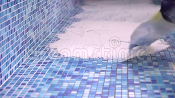 游泳池瓷砖安装工人手安装蓝色游泳池瓷砖与铲子三脚架视频的预览图