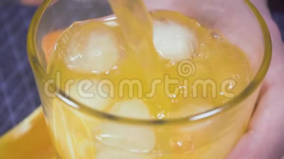 冰在装有橙色苏打水的玻璃杯中漂浮视频的预览图