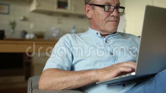 一个成熟的人在网上读新闻使用笔记本电脑坐在厨房的沙发上坏消息问题这就是视频的预览图