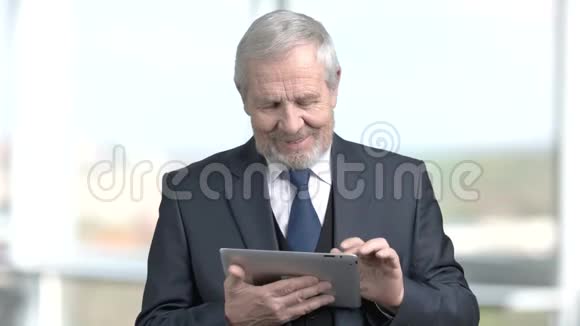 微笑高级商人使用个人电脑平板电脑视频的预览图