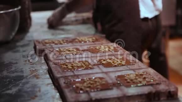 巧克力工厂制作巧克力的过程将液体巧克力倒入表格中加入坚果并冷却视频的预览图