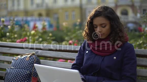 年轻的混血作家在新项目上工作在户外坐着笔记本电脑视频的预览图