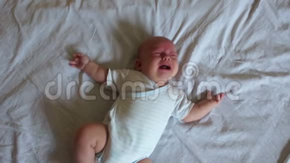 婴儿躺在大床上哭泣这孩子穿着身体和尿布他饿了肚子疼视频的预览图