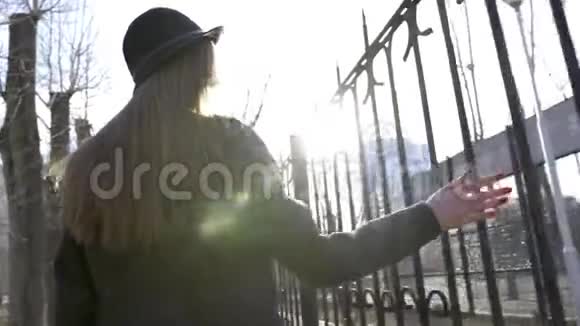 阳光明媚的一天美丽的年轻女子沿街散步行动时髦的年轻女子沿着栅栏走视频的预览图