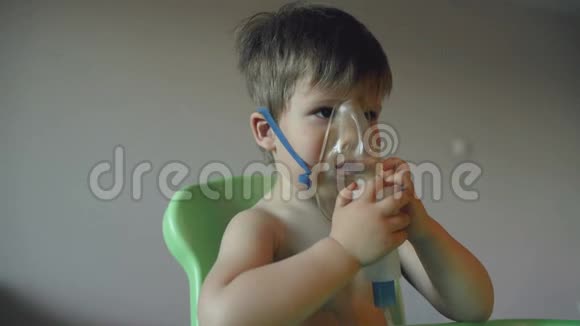 生病的孩子通过吸入雾化器呼吸男孩带着氧气面罩在家里接受治疗视频的预览图