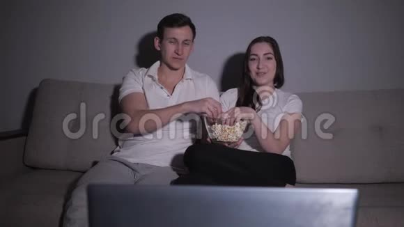 幸福的一对夫妇坐在家里的沙发上看电视电影视频的预览图