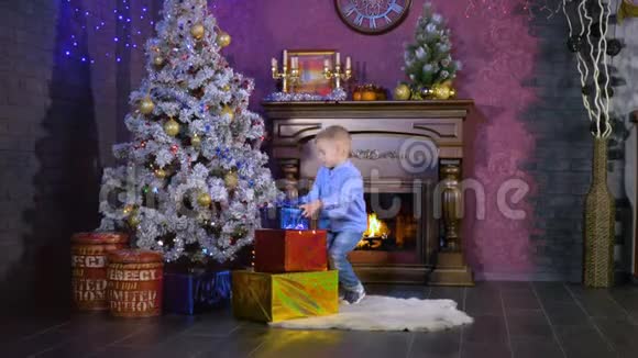 一个男孩把五颜六色的包裹礼物放在圣诞树下视频的预览图
