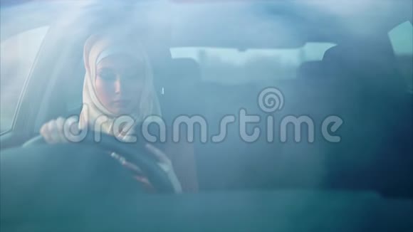 一位身穿头巾的年轻穆斯林妇女坐在后座的车里视频的预览图