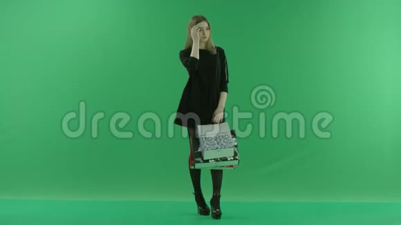 年轻女子拿着购物袋等待彩色钥匙绿色背景视频的预览图