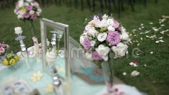 夏季婚礼概念美丽的花束白色和紫色玫瑰镜子食物蜡烛和草地上的花视频的预览图
