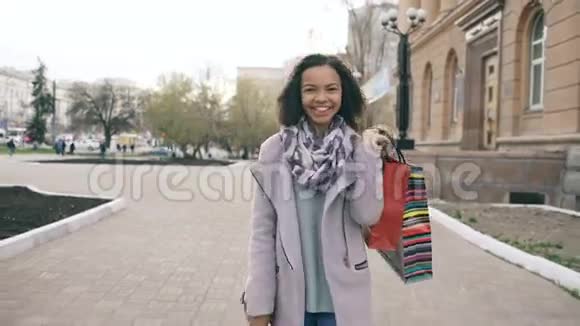 多莉拍摄了一个迷人的混合种族女孩步行走向购物袋和微笑进入相机快乐的年轻女子视频的预览图