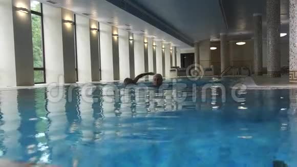 在室内酒店游泳池游泳的老夫妇视频的预览图