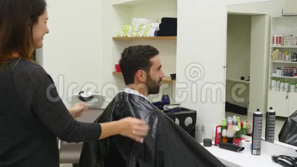 理发师在专业美发沙龙向英俊的满意客户展示带镜子的短发男子视频的预览图