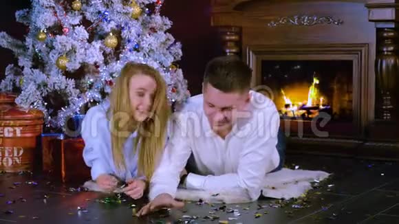 一对年轻夫妇在地板上谈论和玩圣诞纸屑新年庆祝理念视频的预览图