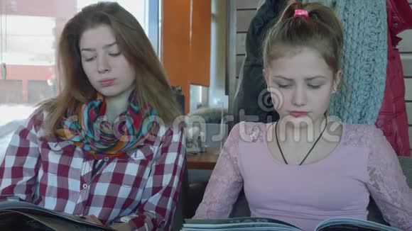 咖啡馆里的两个长头发的金发女郎看着菜单然后互相看着微笑着视频的预览图