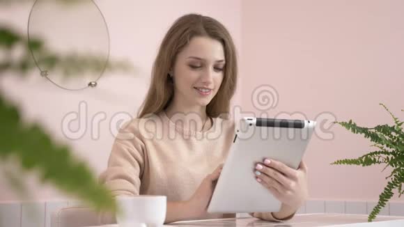 优雅美丽的白种人妇女使用平板电脑发短信打字在60英尺的咖啡馆里微笑视频的预览图