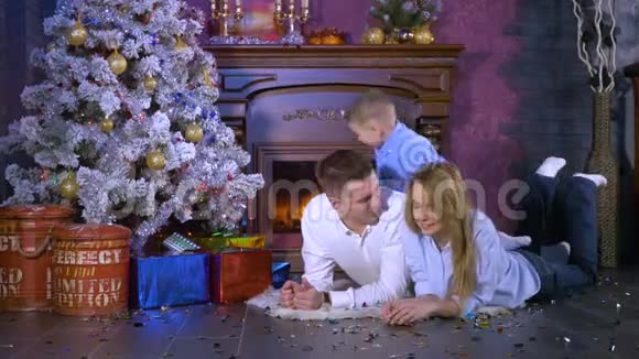 一个男孩围着他的父母在圣诞树下休息圣诞节庆祝概念视频的预览图