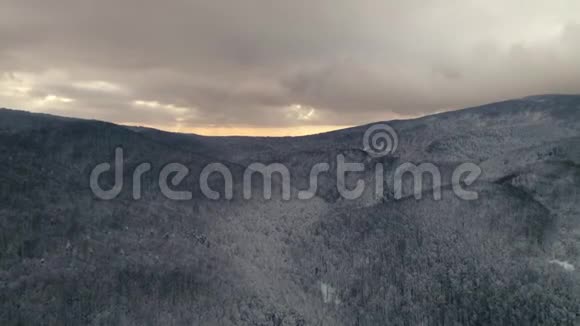 鸟瞰冬季景观日落时飞越雪山森林视频的预览图