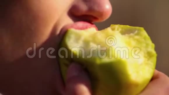 在晴天嘴唇红的特写女郎吃绿苹果视频的预览图