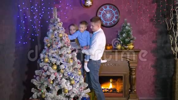 当一个男孩拿一些装饰品时圣诞树会摇晃视频的预览图