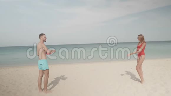 在海滩上玩飞盘的快乐情侣视频的预览图