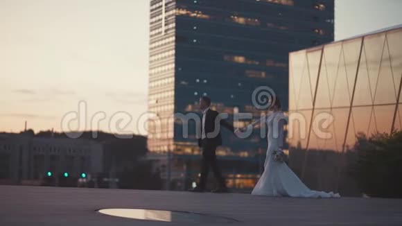 新婚夫妇走在摩天大楼附近视频的预览图