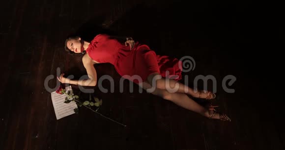 一个穿着红色裙子的年轻时髦女孩死于躺在地板上的不幸的爱情视频的预览图