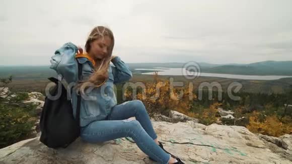 一个年轻的女人坐在山顶上看着美丽的风景想着生活一个女孩视频的预览图