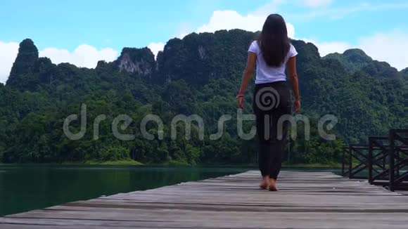 那个女孩正沿着湖边的一个木墩走视频的预览图