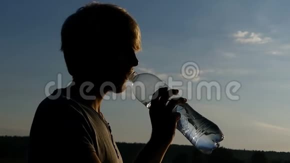 太阳落山时阿尔蒂曼从塑料瓶里喝水视频的预览图