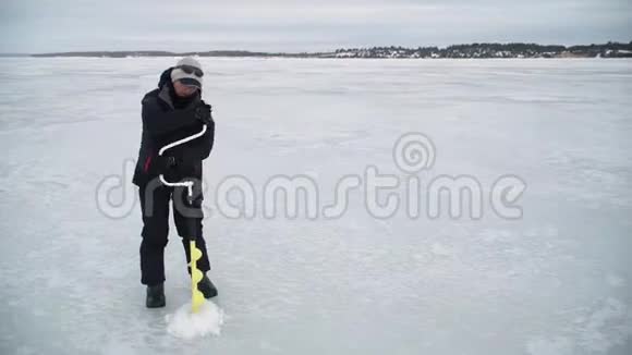 渔民在冰冻的河流上钻洞视频的预览图