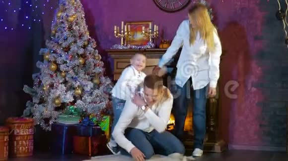 一家人带着一个小男孩在圣诞树旁玩耍视频的预览图