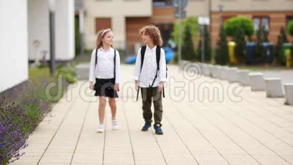 男孩和女孩从学校回来说话孩子们穿着校服背着背包视频的预览图