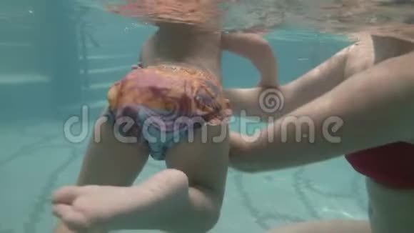 快乐的小男孩和他妈妈一起在游泳池里游泳一位年轻的母亲带着一个小男孩游进来视频的预览图
