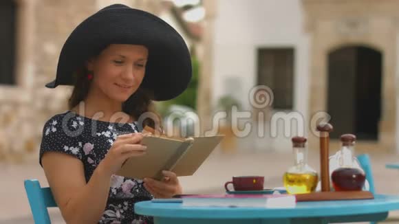美丽的女士翻书在咖啡馆里读有趣的小说视频的预览图
