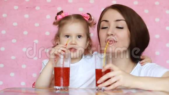 母亲和女儿通过吸管和微笑喝冰沙一位年轻女子和她的孩子的特写肖像视频的预览图