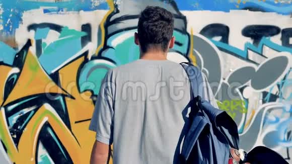 一个带背包的涂鸦艺术家出现在镜头前视频的预览图