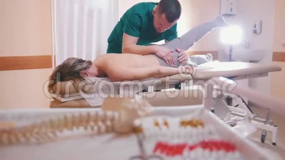 脊椎按摩师按摩躺在按摩台上的年轻女子用他的肘部脊柱模型和视频的预览图