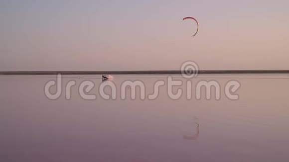 日落时分一个人在湖面上控制着一只训练风筝动作缓慢视频的预览图