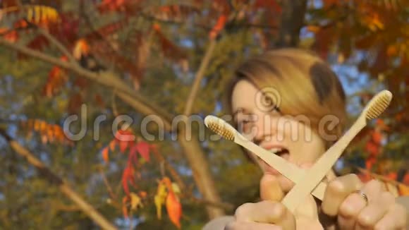 金黄短发的小女孩在秋天阳光明媚的天气里拿着一把竹制牙刷在户外视频的预览图
