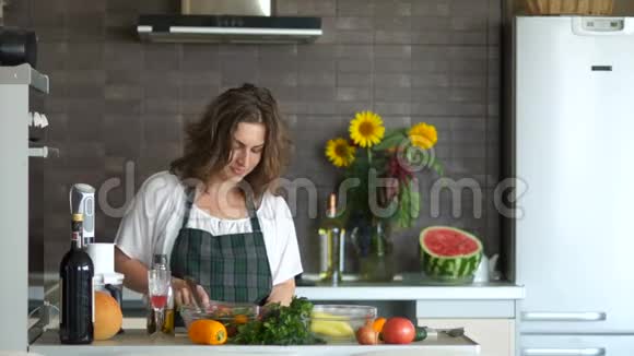 快乐的年轻女人在厨房里用刀跳舞准备沙拉好心情母亲节视频的预览图