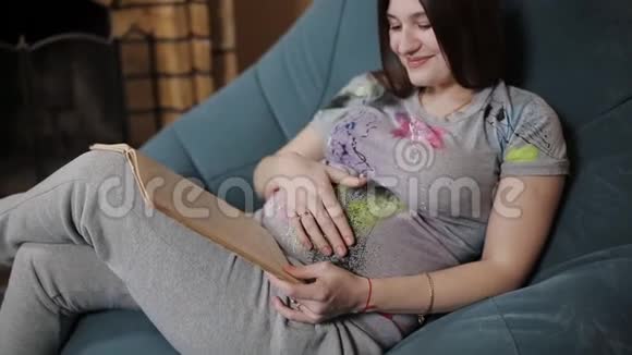 一位孕妇在看书用手纠正她卷曲的冰雹那个女人躺在沙发上放松视频的预览图