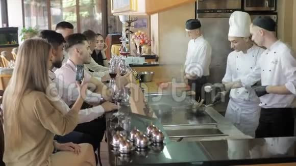厨师们在餐厅的开放式厨房的酒吧桌上为顾客做白色制服的厨师视频的预览图