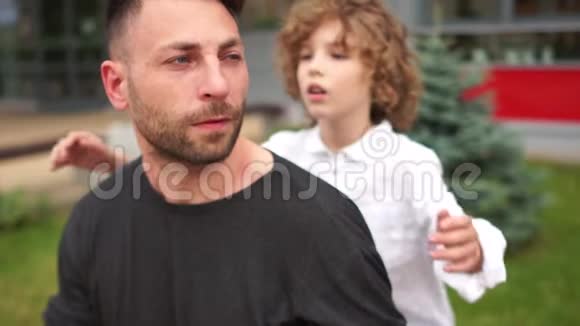 一个卷毛的小学生走近他的父亲拥抱他的肩膀回到学校幸福的家庭视频的预览图